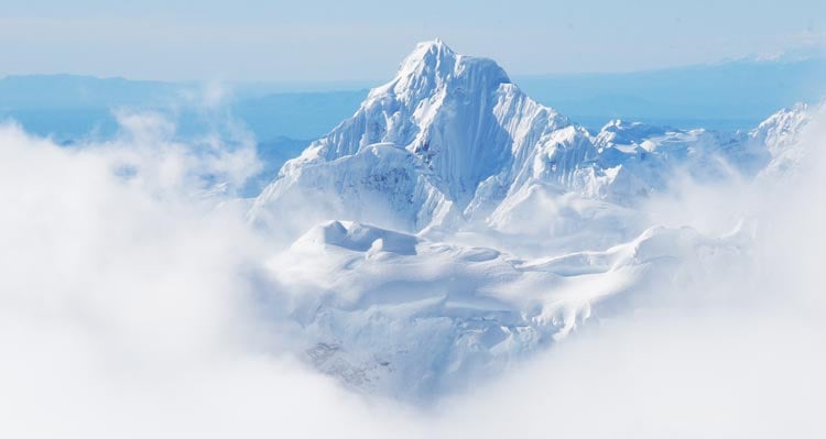 A snow-covered mountain peak pokes out above clouds.