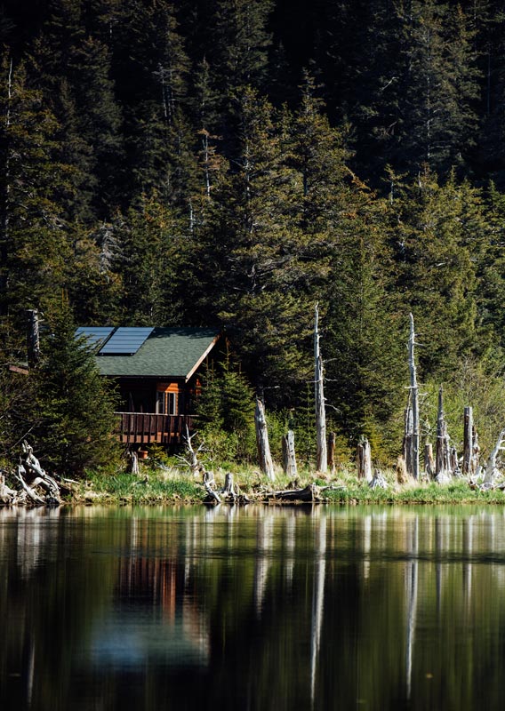 A lodge nestled among trees by calm waters