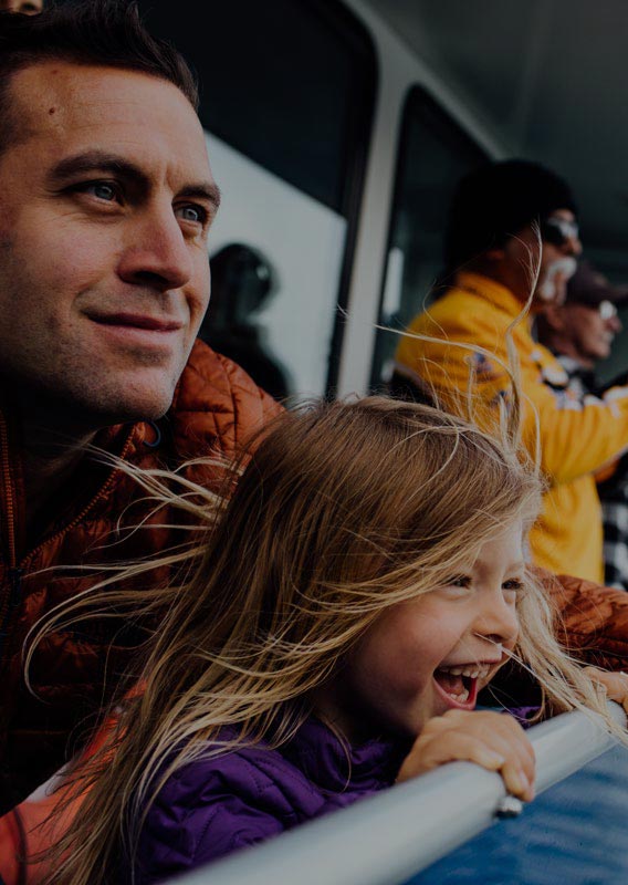 A dad and child stand at the edge of a sightseeing boat