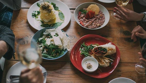 Four plates of dinner on a wooden table.