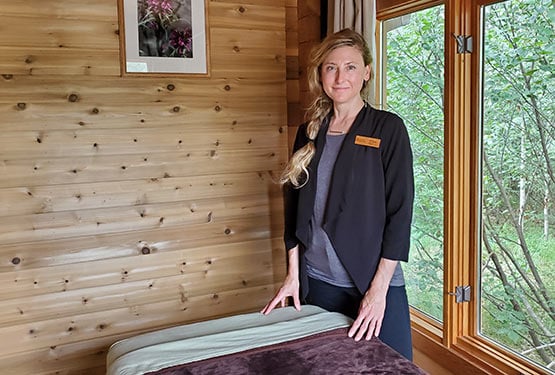 A massage therapist stands by a massage table in a spa room at the Nest Spa