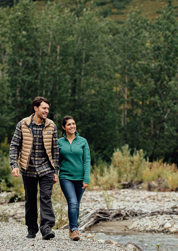 A couple walk along a rocky shoreline