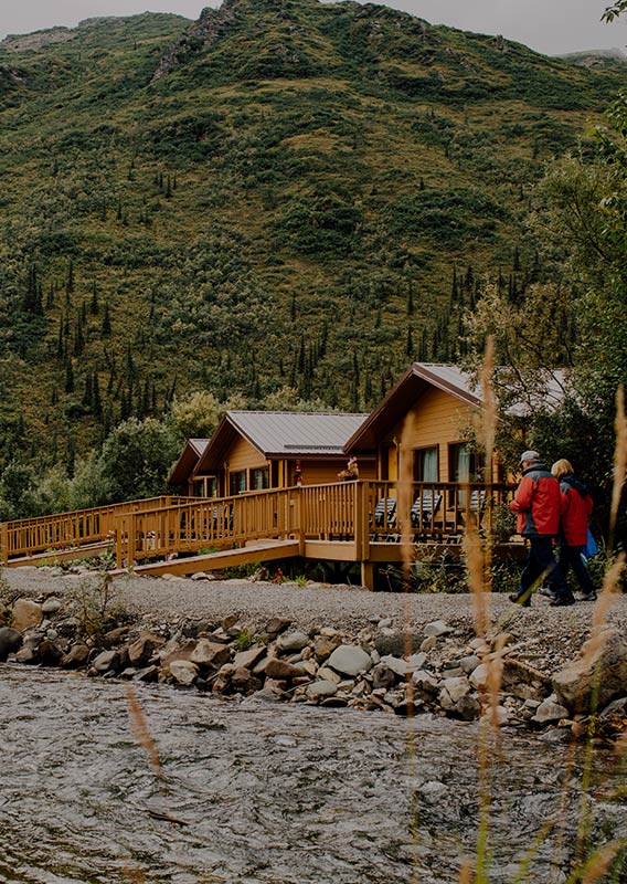 Two people walk along the shore of Denali Backcountry Lodge