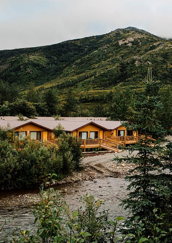 Cabins among trees along a river in mountainous terrain