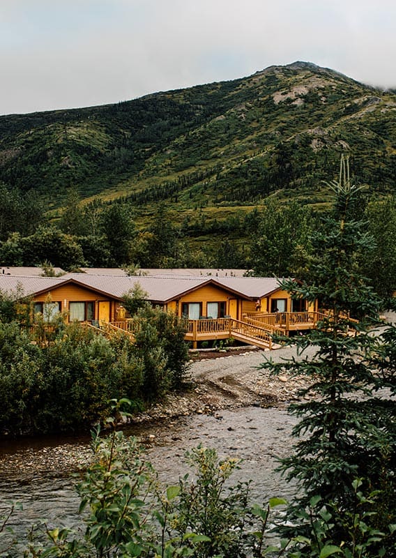 Cabins among trees along a river in mountainous terrain