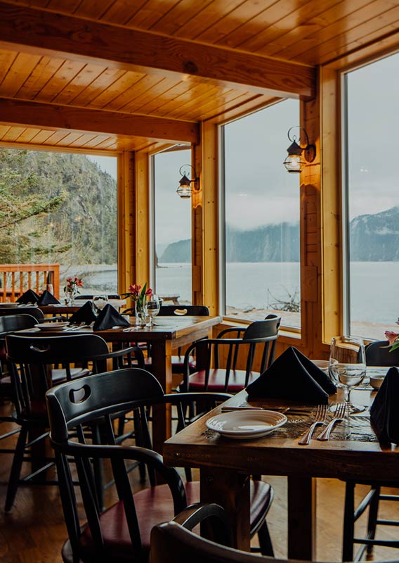 A dining room with large windows overlooking a seashore.