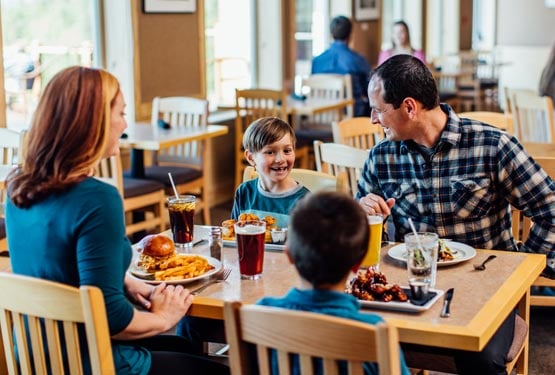 A family sits in a restaurant dining room for dinner.