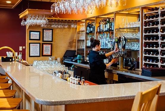 A bartender pours a beer from a draft tap.