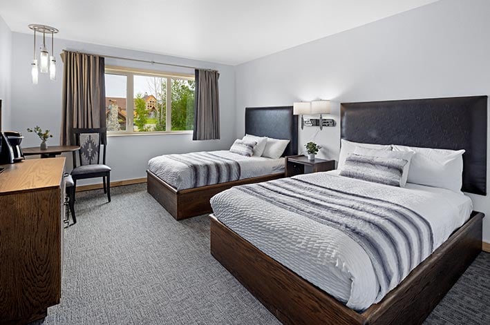 Room with two beds with white and grey decor.