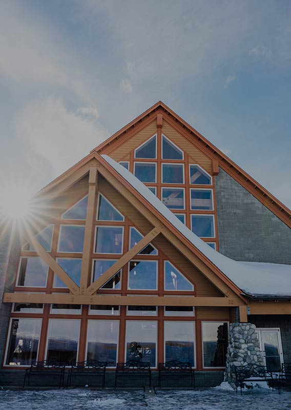 Exterior of lodge in winter with a sunbeam behind the roof