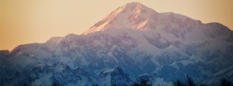 A snow-covered mountain shines in the bright sky.
