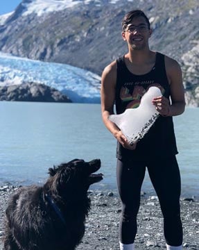 Brandon holding a piece of ice on the seashore near a tidewater glacier.