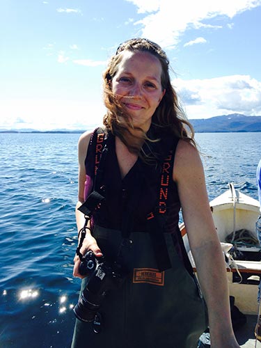 A woman stands on a boat on a sunny, clear day