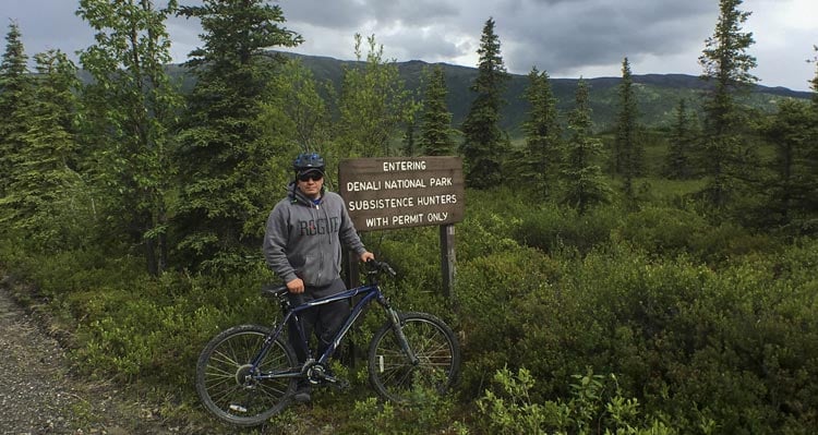 Standing with a bike at the Denali National Park entrance sign.