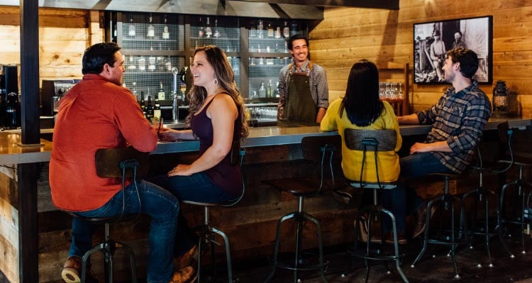 People sit at a bar decorated in a rustic style.