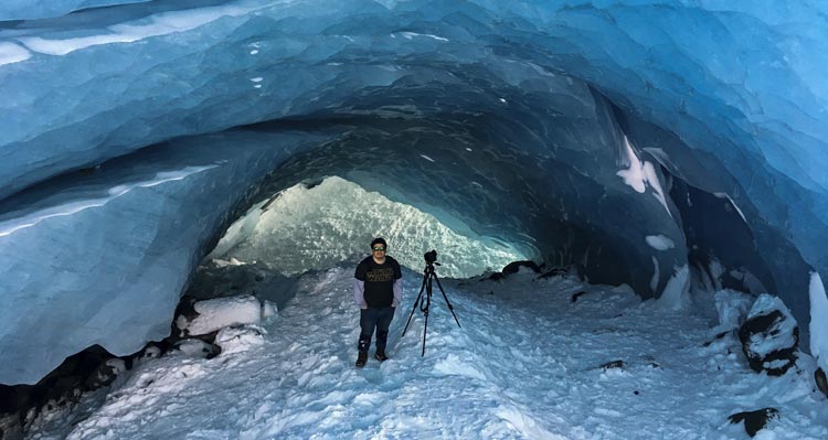 A photographer stands in an icy tunnel.