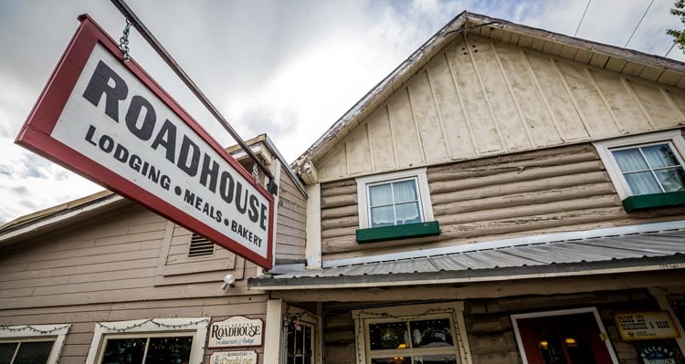 A wooden restaurant, Roadhouse, with a hanging sign.