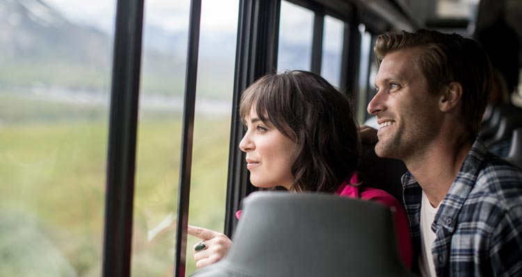 Two people look out a window of a bus.