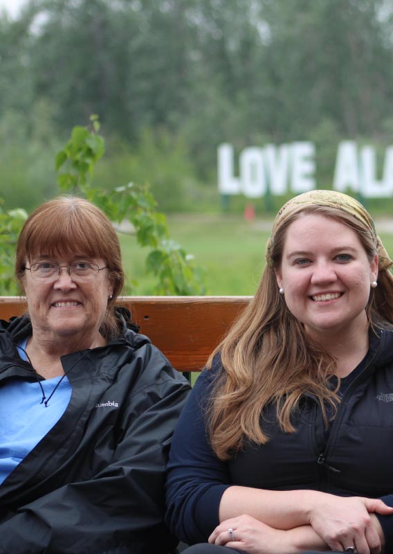 A family sits together on a bench, smiling for the photo.