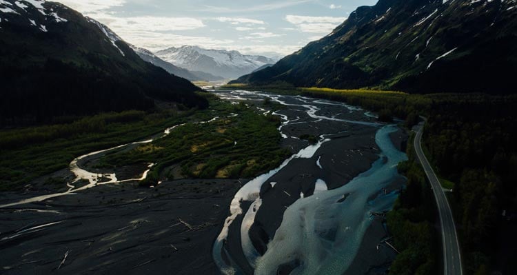 A river braids in a wide valley between rocky mountainsides.
