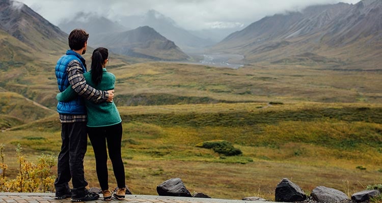 Two people look towards a misty valley.