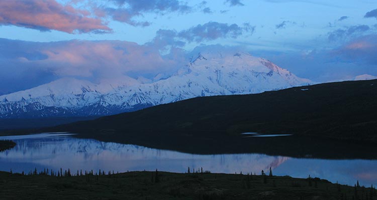 Snow-covered mountains above a dark river.