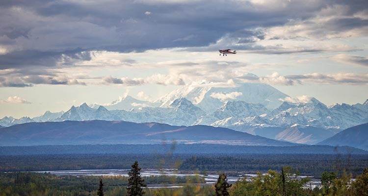 A propeller plane above the tundra and a mountain range.