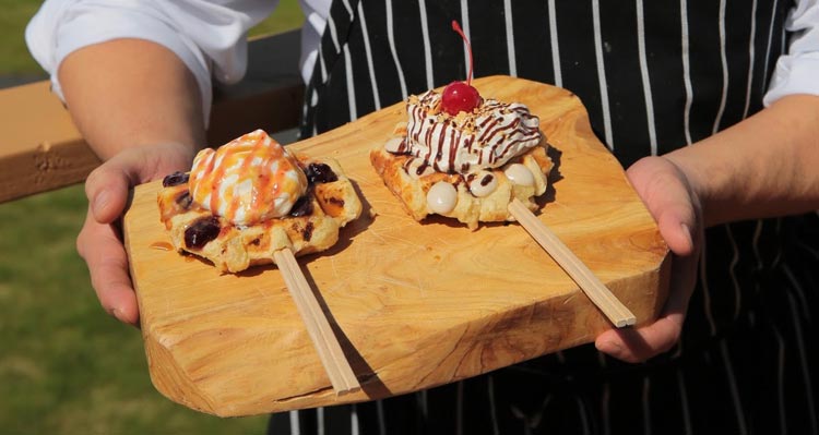Two dessert waffles presented on a wooden board.