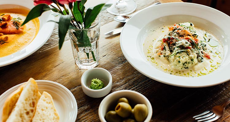 Two bowls of soup on a wooden dining table.