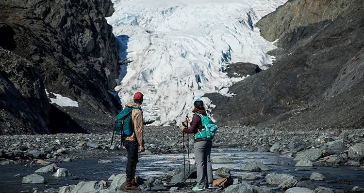 Two hikers look towards a glacier.