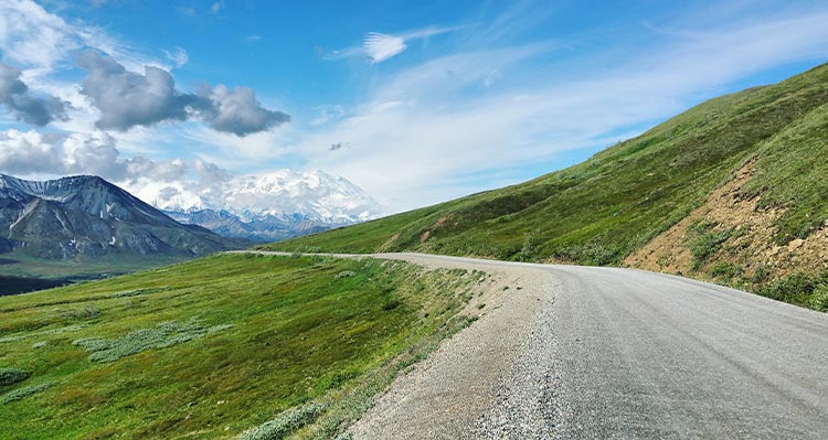 A view down a gravel road along a green hillside