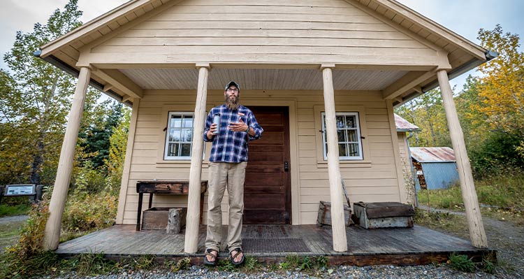 An interpretive guide talks at a small wooden cabin