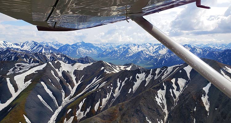 A view from a small plane above snow-covered mountains.