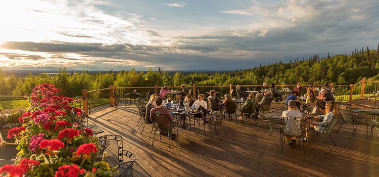 People sitting at dining tables on a patio at sunset
