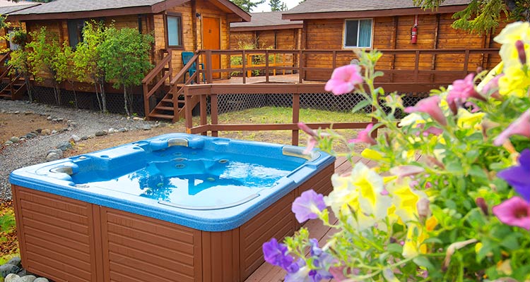 a blue hot tub nestled in between cabins with a stone path