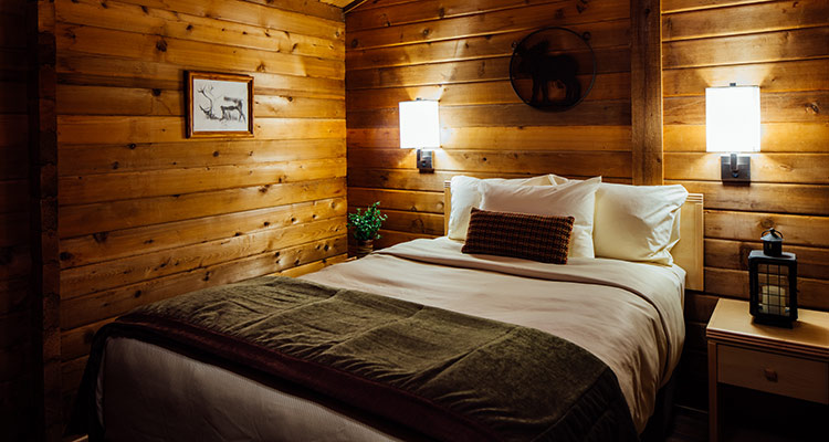 interior of a cabin with a bed, wall sconces and wall art