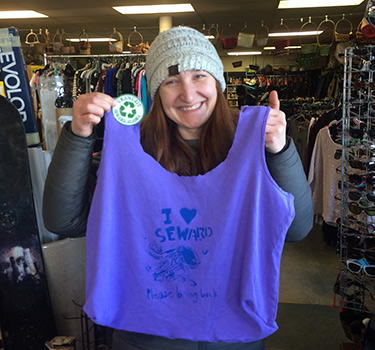 A woman holds up a repurposed t-shirt bag