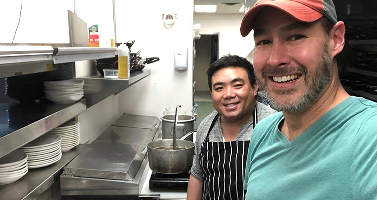 Two people smile in a kitchen.