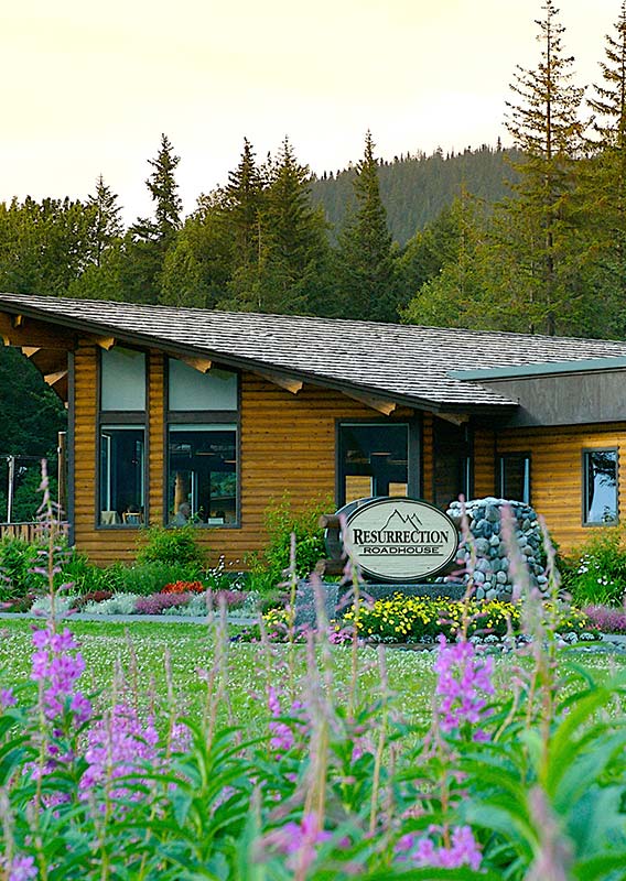 The exterior of a wooden building restaurant, with forest behind it.