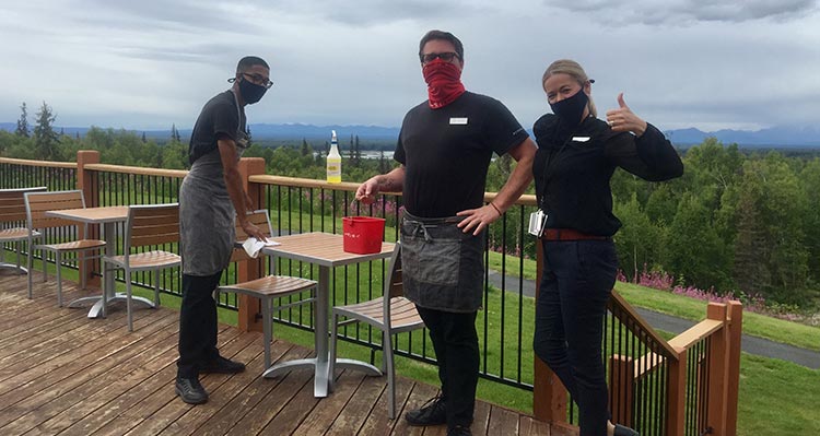 Three people clean patio furniture.