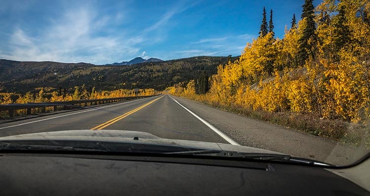 A view out the front of a car down an open road.