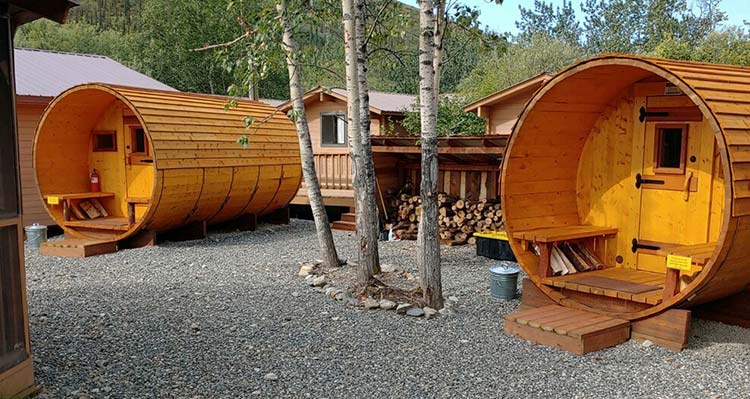 Two wooden saunas next to wooden cabins.