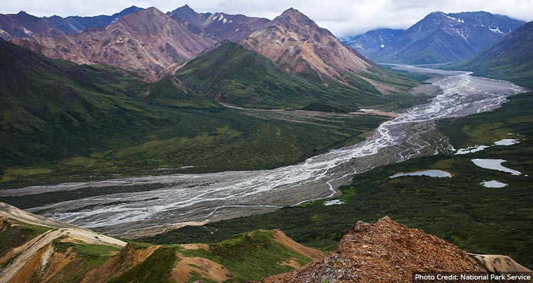 A wide river below tundra and mountains.