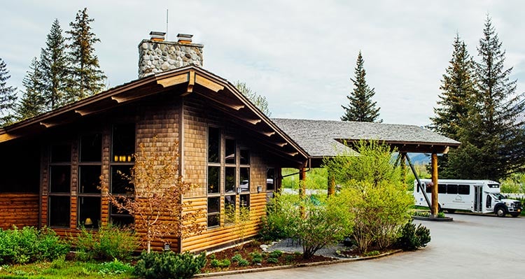 A wooden hotel structure with a stone chimney sits at the top of a hill.