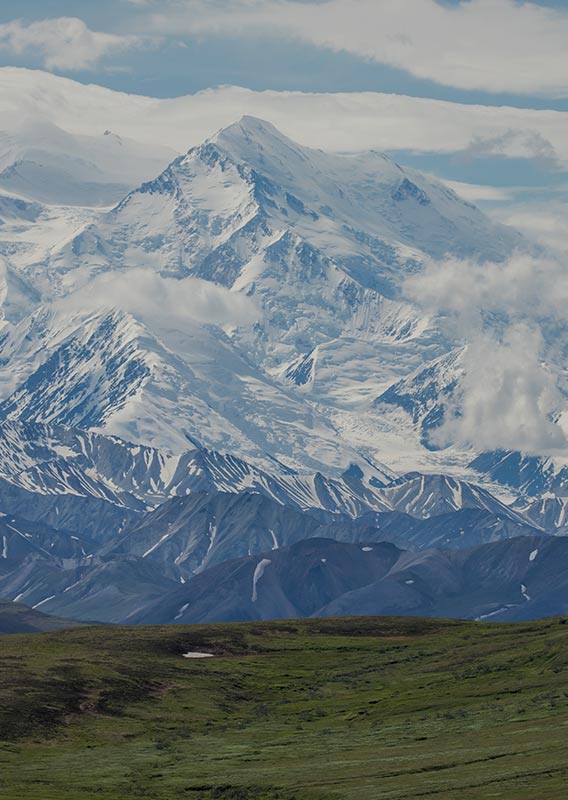 A view across an open plain towards snow-covered mountains.