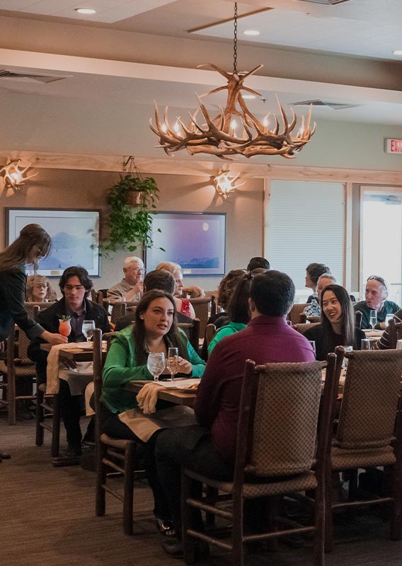 A large group of people sat at long tables in a dining room.