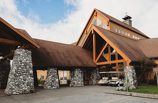 Exterior view of the entrance to a large stone and wooden lodge.