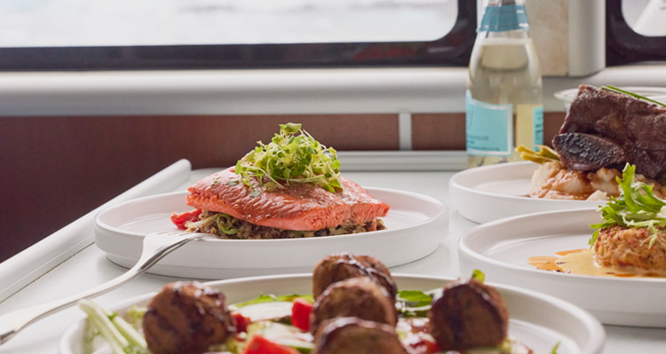 A group of dinner entrees set on a table on a boat.