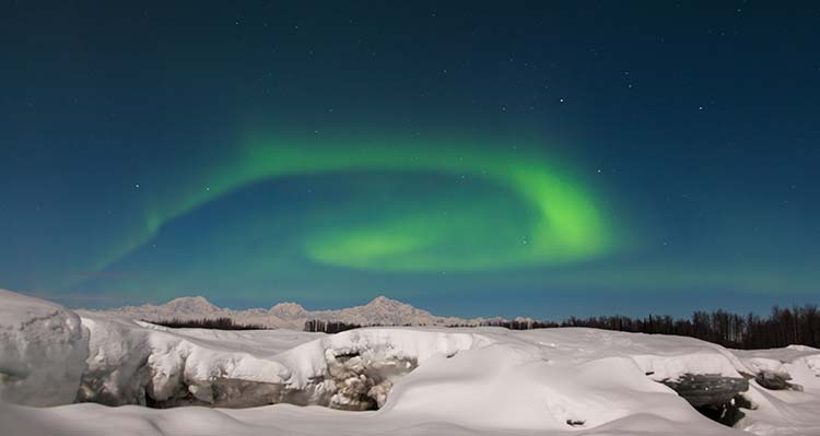 A green spiral aurora over snow.