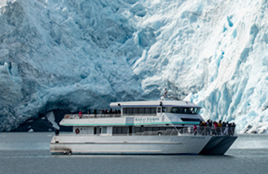 Kenai Fjords Tours boat sailing in front of a glacier